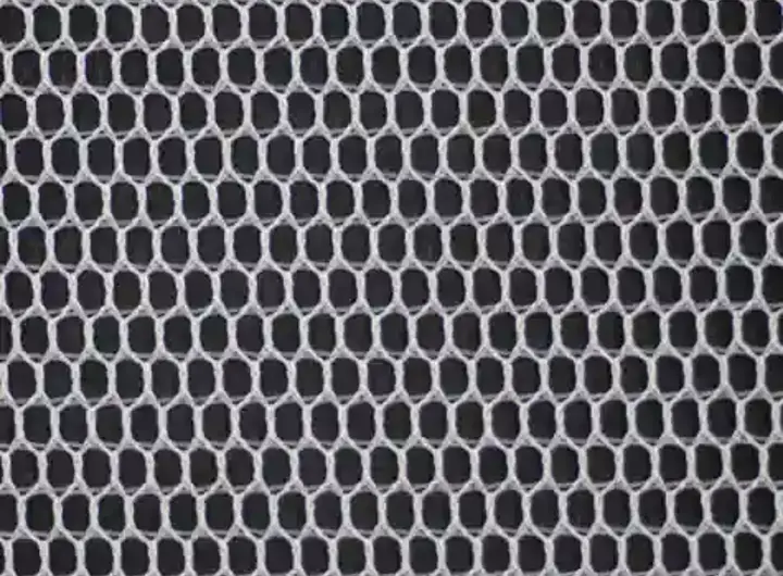 Close-up view of 1928 fabric showing a honeycomb mesh pattern in black and white, ideal for breathable and durable textile applications.