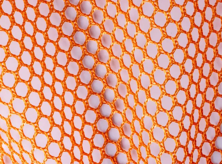 Close-up of 8650R fabric in orange, showcasing a hexagonal mesh pattern designed for visibility, ventilation, and lightweight performance applications.