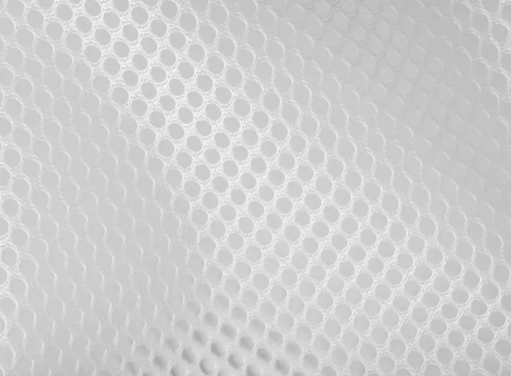 Close-up of 1571 fabric in white, featuring a circular open mesh pattern for enhanced breathability and strength in industrial, safety, or apparel applications.