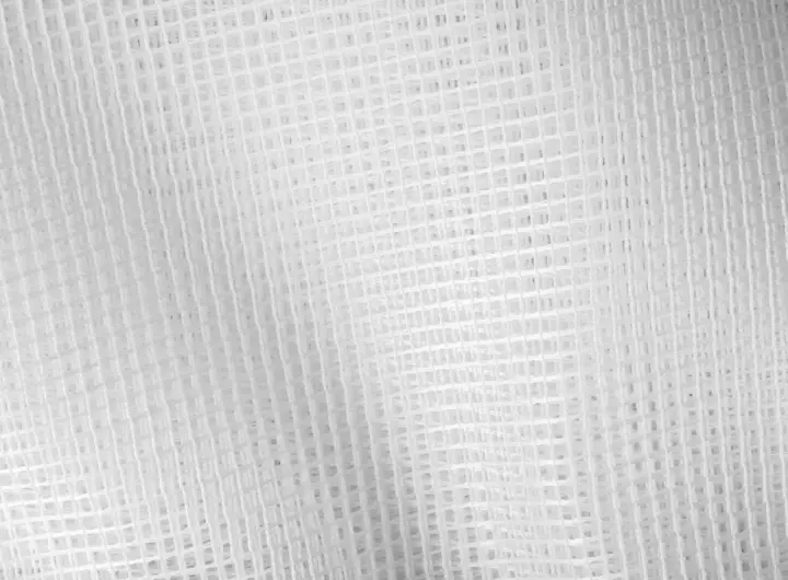 Close-up view of white mesh fabric from Jason Mills, showcasing the intricate grid pattern and texture of the material.