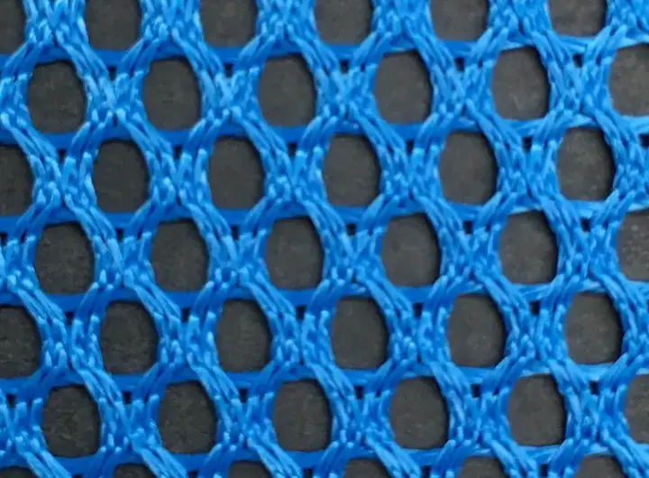 Close-up of 280 Polyester Mesh fabric featuring a royal blue oval mesh pattern over a black background, designed for airflow, durability, and flexibility.