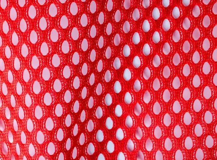 Close-up of 78 fabric in scarlet red, featuring a large oval mesh pattern designed for high breathability and lightweight performance in textile applications.