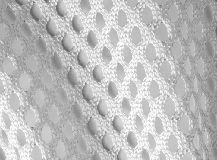 Close-up of 8605 fabric in white, featuring a large open-hole mesh design for enhanced airflow and lightweight comfort in performance or industrial applications.